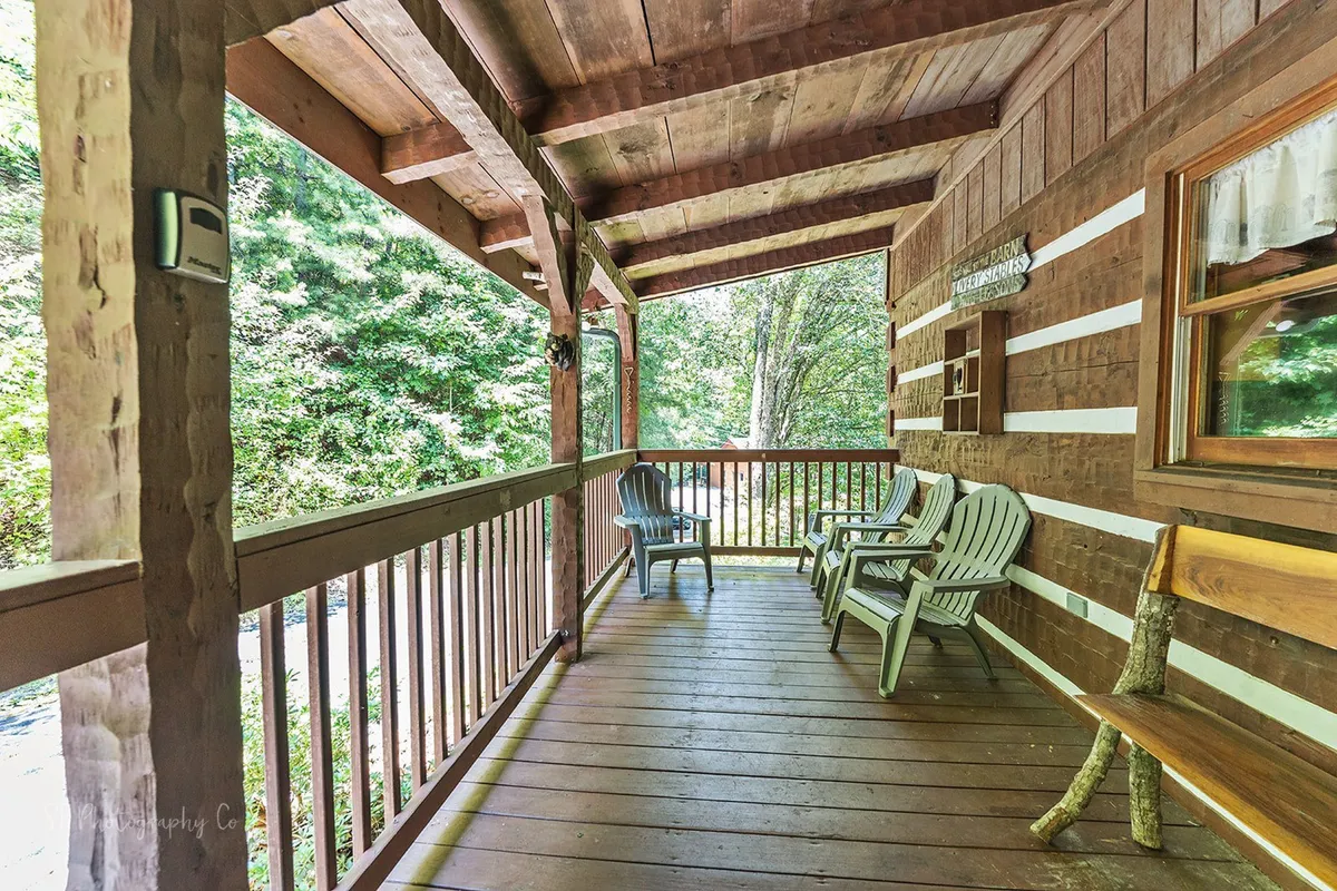 A peaceful deck space featuring wooden railings and rocking chairs overlooking a nature view. The setting is ideal for unwinding while watching sunsets or stargazing in a quiet woodland atmosphere.