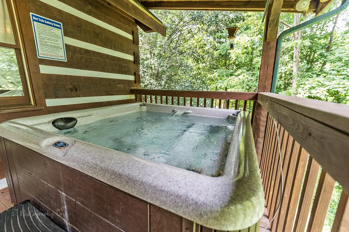 A hot tub is nestled on a wooden deck surrounded by trees. The peaceful setting offers privacy and a direct connection to the natural landscape, perfect for relaxation after a day of adventure.